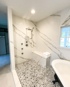 Elegant bathroom featuring a hexagonal tile shower base and classic freestanding tub.