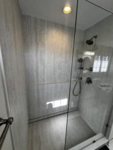 Gray and white porcelain slab shower with gunmetal plumbing